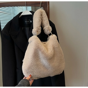 Gros plan d'un sac à main beige en fausse fourrure avec anneaux dorés élégants