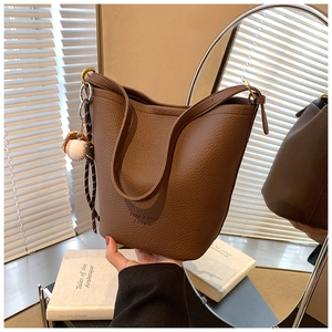 Detail of tan pebble leather shoulder bag with ZSKE brand logo and baseball charm