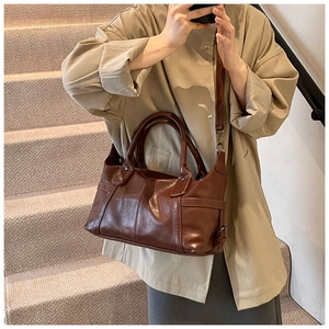 Detail of vintage brown leather tote bag with dual handles and long shoulder strap