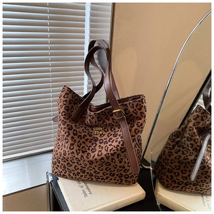 Close-up of leopard print canvas tote bag with brown leather strap and gold hardware