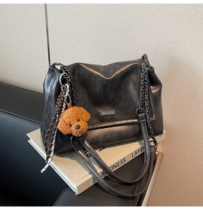 Détail du sac bandoulière rétro gris foncé avec chaîne en métal et breloque ours en peluche