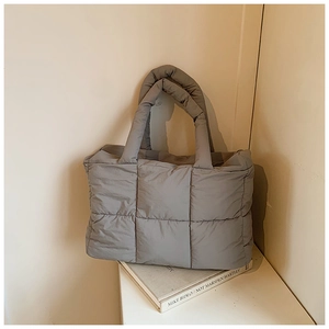 Detail van grijze gewatteerde puffy shopper met zachte handgreep en minimalistische stijl