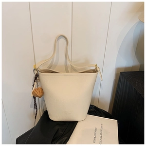 Close-up of cream-white bucket bag with litchi texture and acorn charm detail