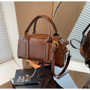 Dettaglio della texture in pelle marrone scuro e hardware dorato vintage sulla borsa