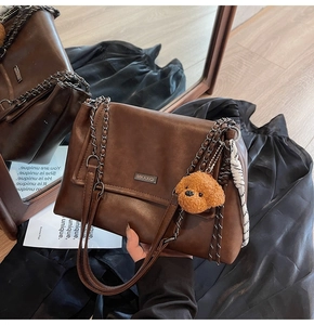 Détail du sac à main en cuir marron vintage avec bandoulière chaîne et pendentif ours