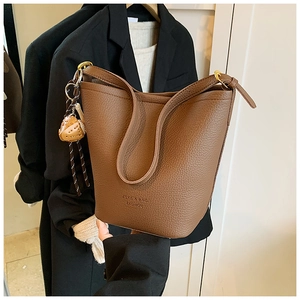 Detail of a brown lychee pattern leather bucket bag with a heart-shaped charm and strap