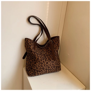 Detail of leopard print tote bag with brown leather straps and gold metal logo