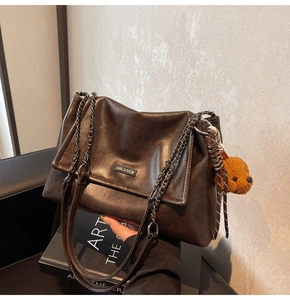 Détail du sac cabas marron foncé avec bandoulière en chaîne et pendentif ours en peluche