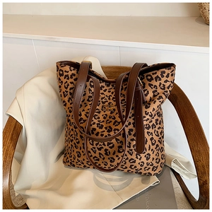 Close-up of leopard print tote bag featuring gold metal logo and brown leather straps