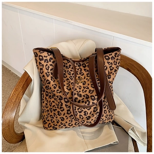 Detailed close-up of leopard print canvas tote bag with leather handles on a wooden chair