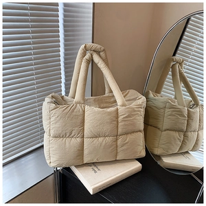 Detailopname van beige gewatteerde shopper met zacht nylon materiaal en vierkant stiksel