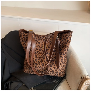 Detail of leopard print tote bag with brown leather straps and gold logo on fabric