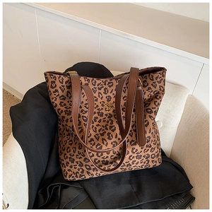 Detail of leopard print tote bag with brown leather straps and gold lettering on sofa