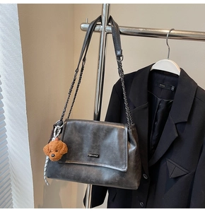 Vue détaillée du cuir vintage avec bandoulière chaîne et pendentif ours en peluche