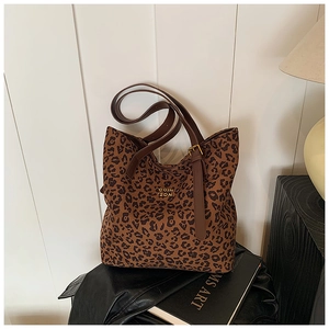 Detail view of leopard print tote bag featuring a leather strap and gold metallic logo