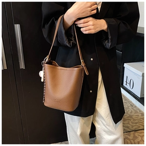 Close-up of brown textured leather bucket bag with a stylish baseball charm detail