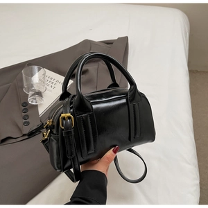 Detail der glänzenden schwarzen Boston-Tasche mit Rundgriffen und goldenen Beschlägen