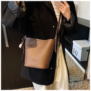 Detail of a brown bucket bag in lychee pattern leather with a white sphere ornament