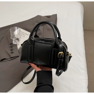 Details einer schwarzen Vintage-Boston-Tasche mit goldenen Beschlägen und Gurt