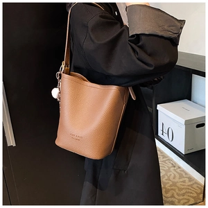 Detail of brown lychee grain leather bucket bag with brand lettering and strap