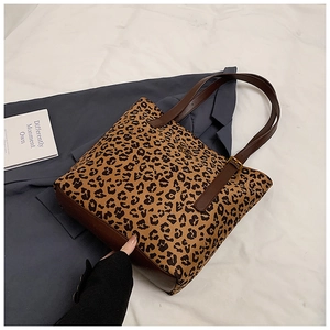 Detail of leopard print tote bag featuring brown faux leather base and long shoulder straps