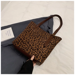 Detailed view of leopard print tote bag featuring brown leather straps and sturdy canvas