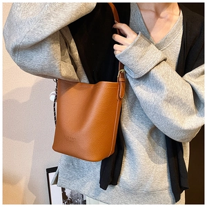 Detailed texture of brown lychee leather bucket bag with baseball charm and buckle