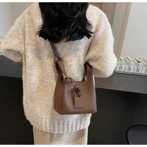 Vue détaillée du sac seau en cuir marron montrant la bandoulière réglable sur un mannequin