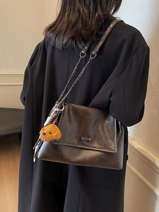 Sac bandoulière rétro en cuir marron foncé avec chaîne et breloque ours sur un modèle