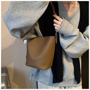 Detailed view of brown lychee grain leather bucket bag with adjustable shoulder strap