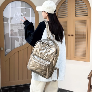 Detail eines gesteppten Rucksacks in Champagnergold mit geflochtenem Seil am Reißverschluss