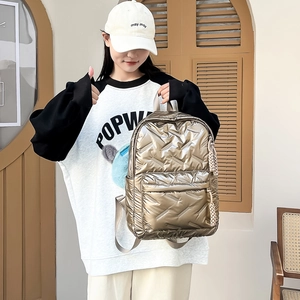 Detailansicht des champagnergoldenen gesteppten Rucksacks mit Metallic-Finish und Anhänger