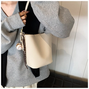 Detail of cream white leather bucket bag with lychee texture and baseball pendant