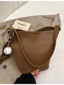 Brown litchi grain leather bucket bag with sporty baseball charm and wide strap