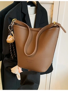 Retro brown lychee leather bucket bag with wide strap and baseball glove charm