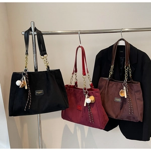 Three leather tote bags in black, burgundy and coffee with metal chain straps and charms