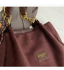 Close-up of suede texture and gold chain strap on the dark brown tote handbag