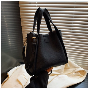 Detailed close-up of black lychee grain leather bucket bag with gold metal buckles