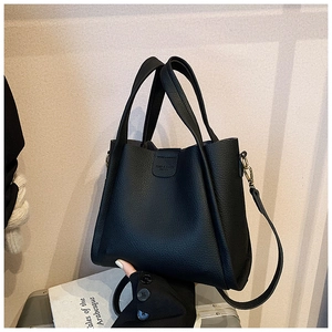 Detail of black pebbled leather bucket bag featuring gold hardware and wide top handles