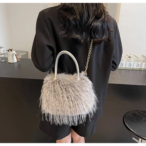 Gray plush bucket bag with fuzzy texture and pearl-decorated handle on a black blazer