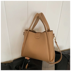 Detail of khaki pebbled leather bucket bag with top handles and logo magnetic clasp