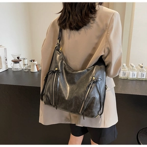 Close-up of vintage black leather tote bag with gold zippers and tassel drawstring details