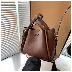 Detailed close-up of dark brown lychee pattern leather handbag with gold metal buckles