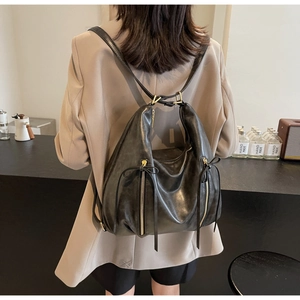 Detail of leather backpack with dual vertical zippers and gold-tone tassel hardware