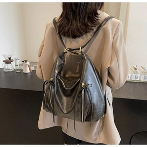 Detail of black leather backpack featuring decorative zippers and elegant leather bow accents