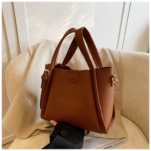 Detail of brown lychee texture leather handbag featuring brand logo and metal buckle