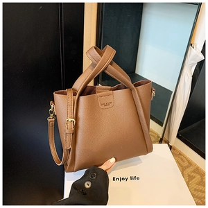 Detail of caramel brown litchi grain leather tote with wide handles and strap
