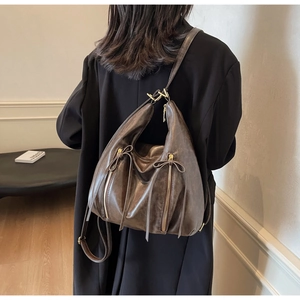Detail of dark brown vintage leather tote with side zippers and bow tassel decoration