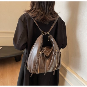 Detail of a dark brown vintage faux leather backpack with metallic zippers and tassels