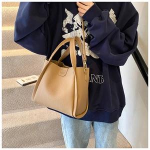 Detail of khaki pebbled leather tote bag with gold hardware and embossed logo